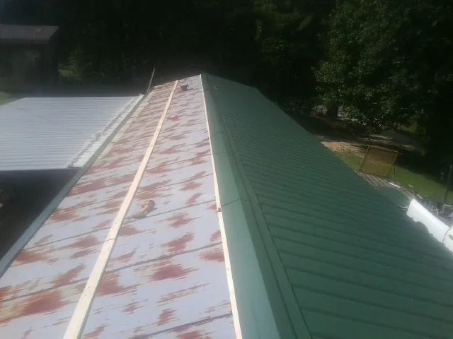Old rusted panels beside newly installed green metal roofing — Wind Damage Roof Repair by Roofing Brothers in West Milton