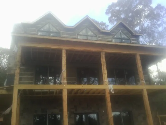 Dormers and porch framing on a large log home under construction — Roof Coating work by our crew in West Milton