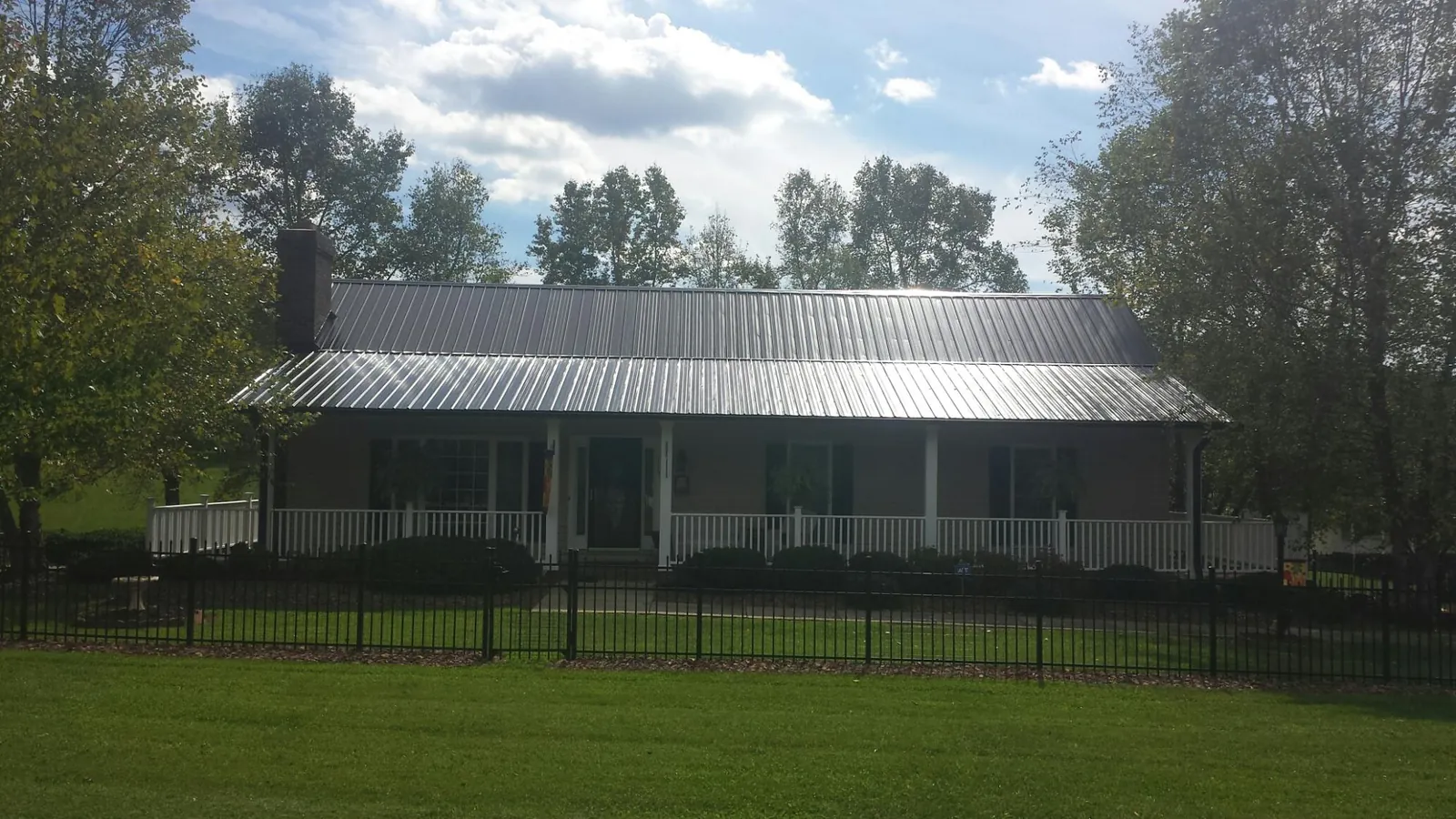 Gray metal roof on a brick ranch with a full width front porch — Gutter Guard Installation work by our crew in West Milton