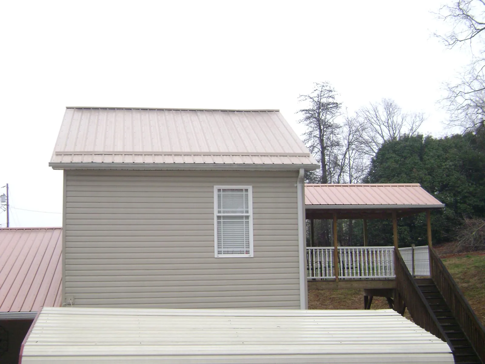 Tan metal roofs on a two story addition and attached porch, from a Roof Replacement job in West Milton