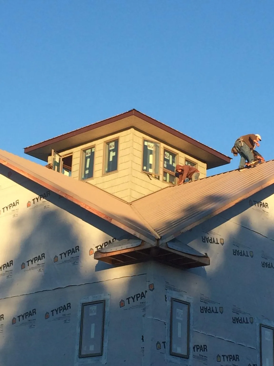 Roofers working around a rooftop cupola on a new metal roof at sunset — Roof Waterproofing in West Milton by Roofing Brothers